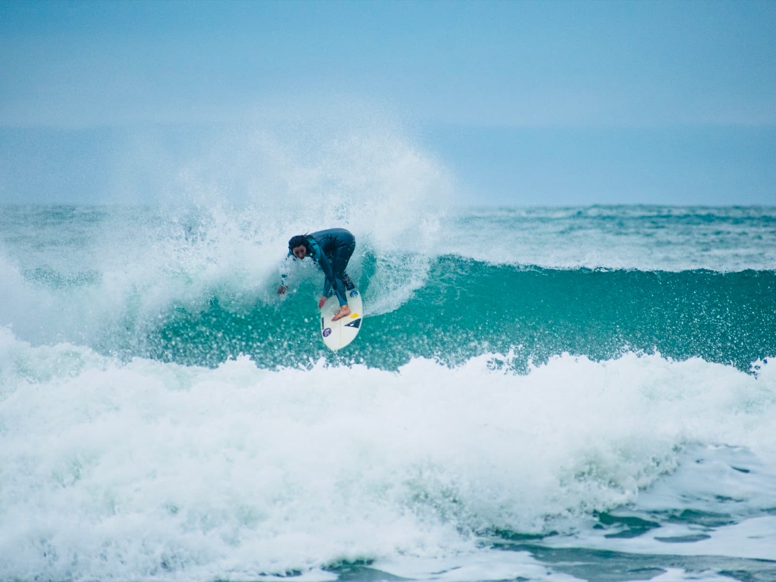 A surfer doing a turn on a powerful wave at Praia Mole, Florianópolis, with spray all around.
