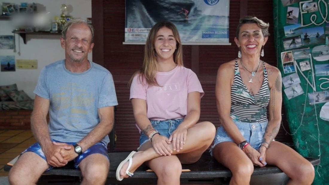 Three members of the family sitting side by side on a bench, smiling